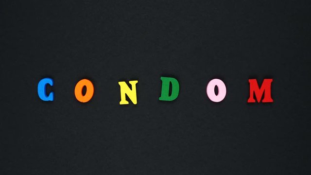 Word "condom" formed of wooden multicolored letters. Colorful words loop.