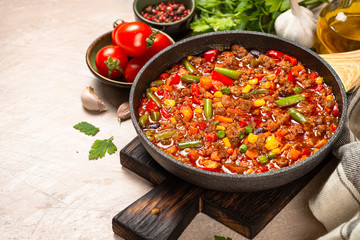Chili con carne in skillet on light stone table.