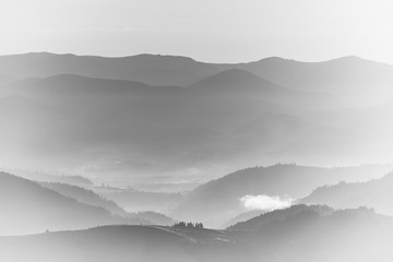 View of the top on fantastic sunlight of beautiful scenery mountains range at sunrise. Layers of mountain and haze in the hills at distance. Black and white landscape. High key photography background.