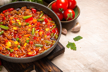 Chili con carne in skillet on light stone table.