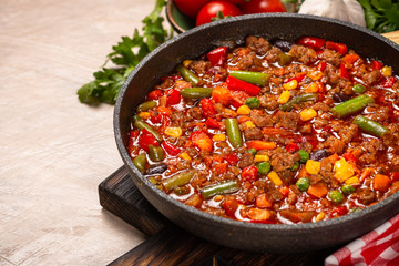 Chili con carne in skillet on light stone table.
