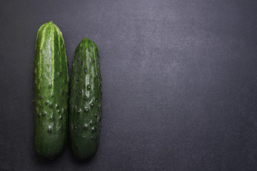 Fresh green cucumbers. Vegetables on a black textured background.