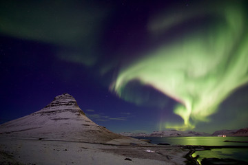 Strong Northern light pass over a beautiful mountain covered with snow with clear sky 