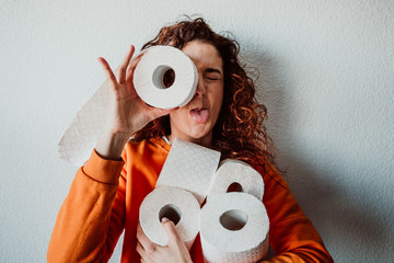 .Young woman hoarding a lot of toilet paper at home. Madness caused by the coronavirus health...