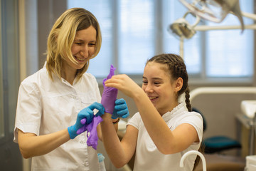 Schoolgirl with the help of dentist woman wear medical gloves in the dental clinic.