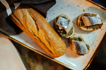 White bread with pesto and herring on a wooden plate.