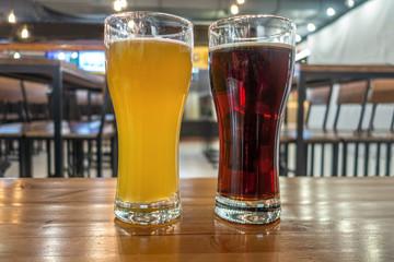 two glasses of cold fresh white and dark beer on a table in a pub
