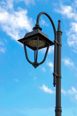 LED lamp on blue background. Blue sky with fluffy clouds