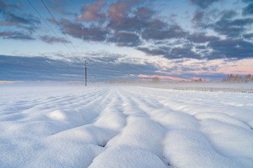 Obraz premium Winter sunrise over snow covered field with round shape snow piles .