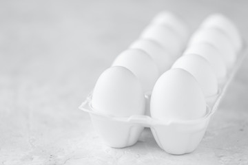 Group of white eggs in the package, grey background, space for text.
