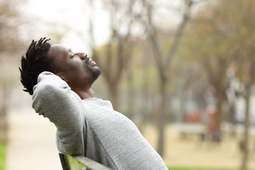 Black man relaxing on a bench in a park
