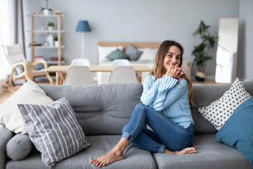 Relaxed smiling woman sitting on sofa at home.