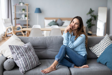 Relaxed smiling woman sitting on sofa at home.