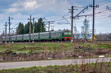 Obraz premium Railroad Train passing by a wooden rural house in a web of wires