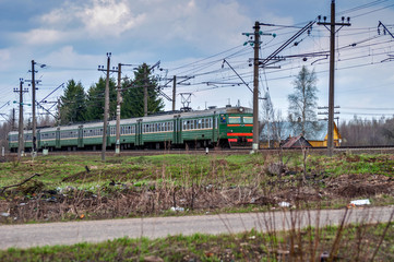 Railroad Train passing by a wooden rural house in a web of wires