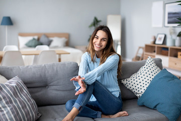 Obraz premium Happy woman resting comfortably sitting on sofa in the living room at home.