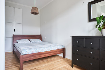 Fototapeta na wymiar double wooden bed in a minimalistic white bedroom