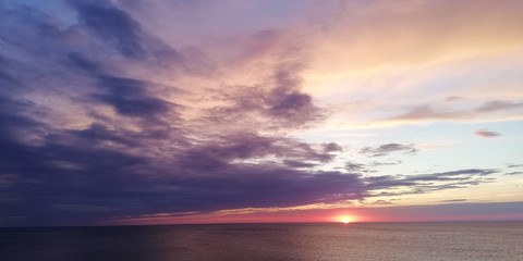 Fototapeta na wymiar Dramatic disturbing landscape of stunning sea sunset in purple and orange tones. Dark clouds in the sky of amazing beauty. The mood of flight, infinity, tragedy