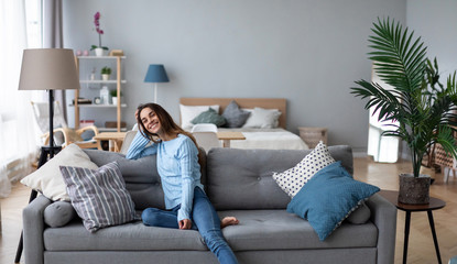 Tranquil smiling millennial woman leaning on sofa.