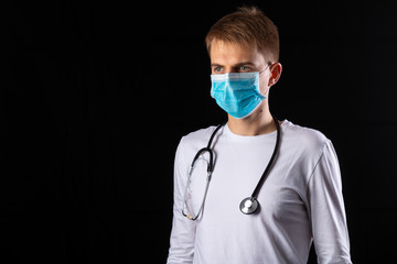 Young doctor in medical mask on a black background