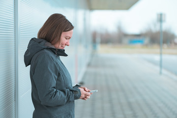 Smiling woman text messaging on mobile phone outdoors