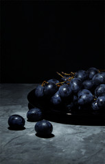 bunch of grapes on a plate black grapes