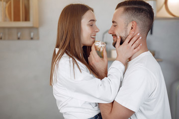 Cute couple in a kitchen. Lady in a white shirt. Pair at home