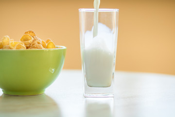 cornflakes in the green dish, milk is flowing into the glass
