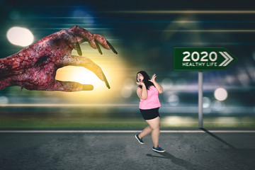 Overweight woman escaping from a zombie hand