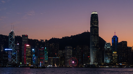 Naklejka premium One international finance center surrounded by another tall buildings in Victoria Harbor at night.