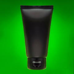 Black tube on a green background. Cream in a tube. Paste in a tube. Ointment in a tube.