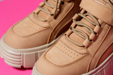 Fototapeta na wymiar brown leather women shoes with high soles on a pink background. fashion footwear