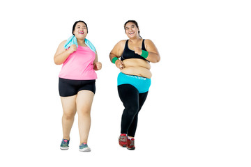 Young overweight women jogging together in studio