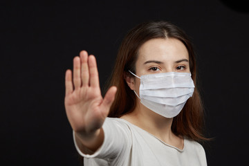 a girl in a mask shows a stop gesture fearing for the health of people