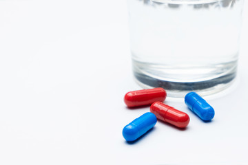 Red and blue tablets with a thermometer on a white background. Treatment of flu /cold/coronavirus.