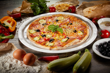 Flatlay of Italian pizza on wooden background. Rustic homemade pizzas with salami, bacon,  cheese, eggs and raw vegetables on shabby wooden background. Healthy vegetarian fungi pizza