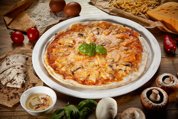 Flatlay of Italian pizza on wooden background. Rustic homemade pizzas with salami, bacon,  cheese, eggs and raw vegetables on shabby wooden background. Healthy vegetarian fungi pizza