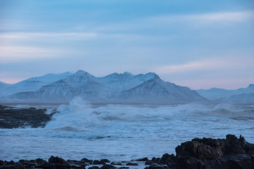 Wild coast in Icealnd with snow covered mountains in the background