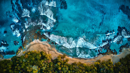Aerial drone photo of a blue tropical lagoon surrounded by white sand of an exotic beach and palm trees. View from the top
