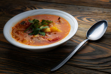 Kharcho soup with meat and rice on a wooden table, closeup, shallow depth of field. Concept, healthy food.