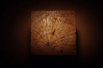 Wooden cube in the beam of light as a product display or background. Top view. Copy space