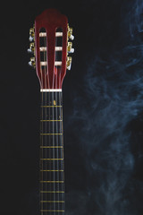 Acoustic guitar in smoke on the black background. musical instrument. strings on the guitar neck