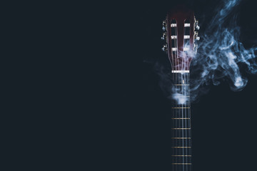 Acoustic guitar in smoke on the black background. musical instrument. strings on the guitar neck
