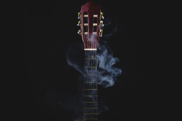 Acoustic guitar in smoke on the black background. musical instrument. strings on the guitar neck