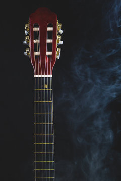 Acoustic guitar in smoke on the black background. musical instrument. strings on the guitar neck