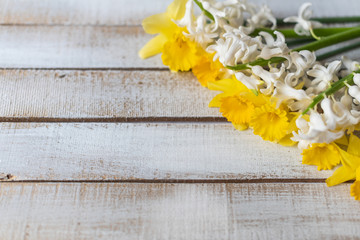yellow daffodils and white hyacinths flowers on a white wooden background in springtime