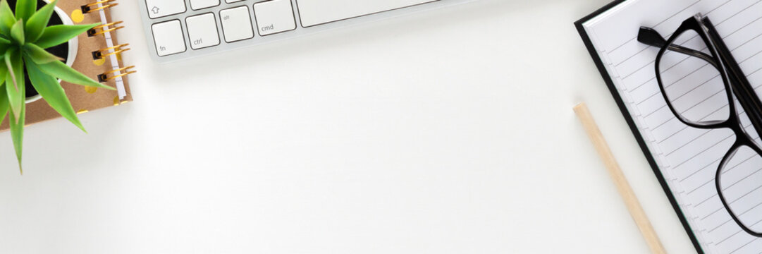 Office desk with white empty space for text. Copy space. Keyboard, open notebook, glasses and plant. Office accessories. Panorama