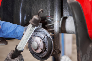 Rusty drum brakes, rear on red car. Change the old to new brake disc on car in a garage. Auto...