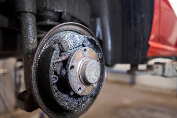 Rusty drum brakes, rear on red car. Change the old to new brake disc on car in a garage. Auto mechanic repairing