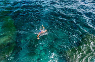 Obraz premium a man dives with glasses and tube and bathes in the sea with turquoise blue color